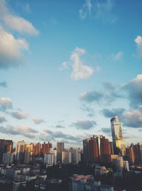 Low angle view of skyscrapers against cloudy sky