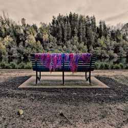 Hooded chairs against trees on landscape against sky