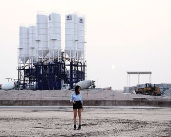 Woman standing against industrial building