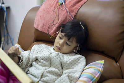 Cute girl relaxing on sofa with electrodes on head