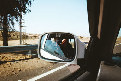 Point of view, perspective, reflection of car on side-view mirror, road trip