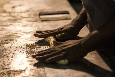 Midsection of man kneading dough