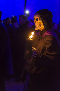 Midsection of woman standing by illuminated light at night