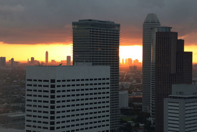 Modern buildings in city against sky during sunset