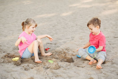 Siblings playing on sand at beach