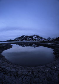 Scenic view of lake by snowcapped mountain against sky