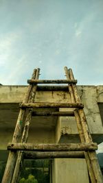 Low angle view of bamboo ladder and built structure against sky