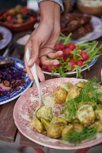 Cropped hand of woman picking prepared potatoes from plate during social gathering on terrace