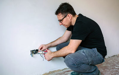 Young man looking away against wall