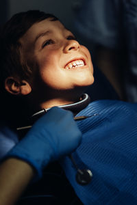 Dentist operating cheerful boy in medical clinic