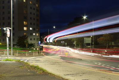 Light trails on city street amidst buildings at night