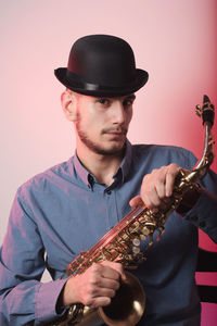 Portrait of saxophonist wearing hat against wall