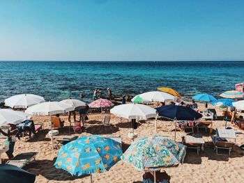 Deck chairs and parasols on beach against clear blue sky