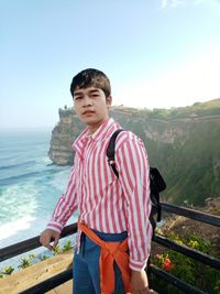 Portrait of young man standing against sea