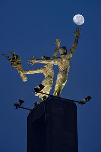 Low angle view of angel statue against clear blue sky