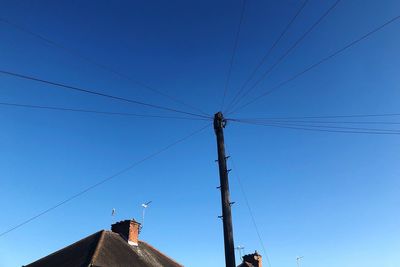 Low angle view of birds on cable against sky