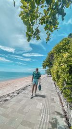 Rear view of man walking on road against sky