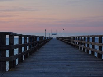 Empty pier over sea against sky during sunset