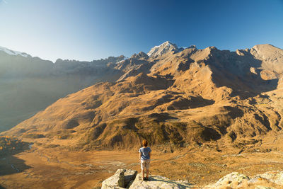 Rear view of woman standing on mountain against clear sky