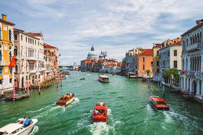 People on gondolas in canal passing through city buildings