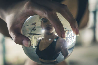 Close-up of hand holding crystal ball with reflection