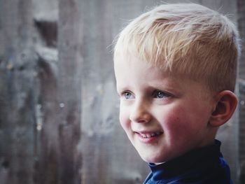 Close-up of cute boy looking away while standing against wall