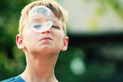 Close-up portrait of boy looking through bubble