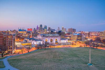 Illuminated city buildings against blue sky