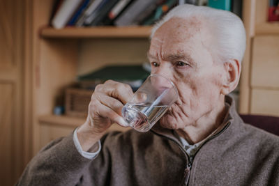 Portrait of man drinking from glass at home