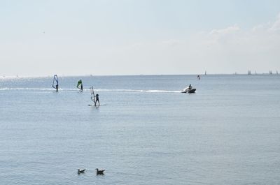 People swimming in sea against sky