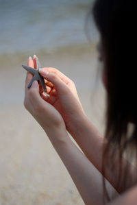 Close-up of woman hand holding sand at beach