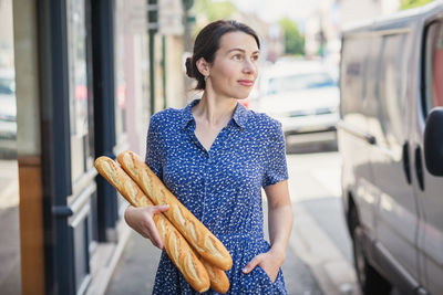 Young woman buying a french baguette