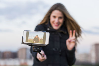 Portrait of smiling young woman photographing camera