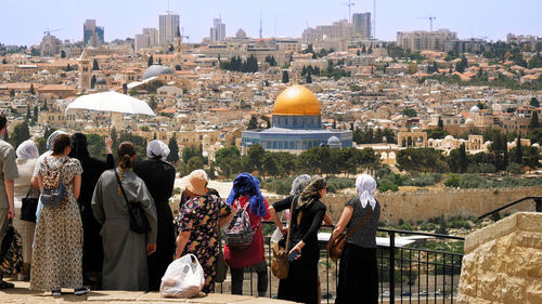 Rear view of people looking at cityscape during sunny day