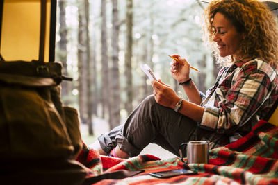 Woman writing in book while sitting in tent 