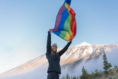 Woman with arms raised against sky