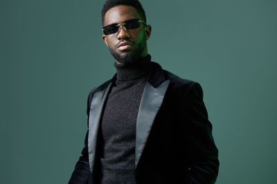 Portrait of young man standing against black background