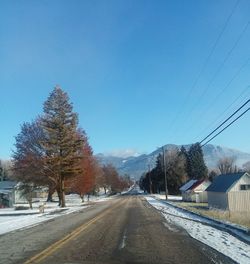 Road amidst trees against clear sky during winter