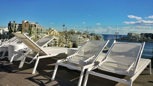 Close-up of empty chairs and tables at beach against clear sky