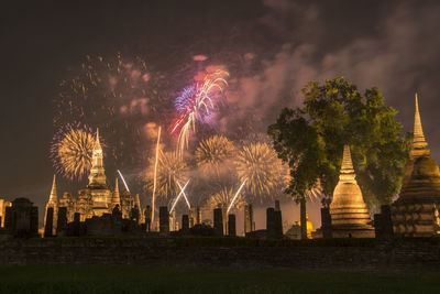 Firework display in city against sky at night