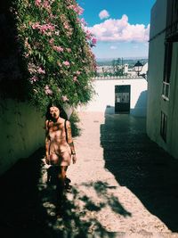 Full length of shirtless man standing by tree against sky