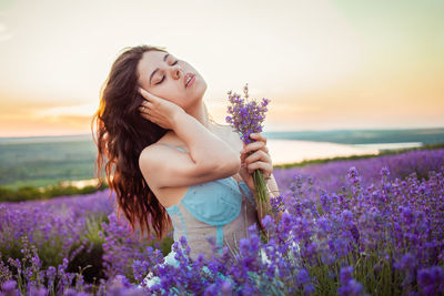 A beautiful young girl against the sunset and a beautiful sky in a lavender field. 