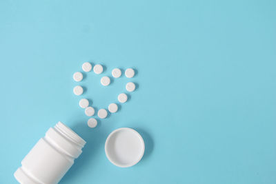 Pills spilling from bottle against blue background