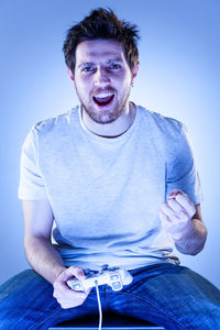 Portrait of man sitting on sofa against gray background