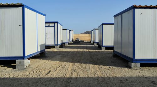 Empty beach huts against clear blue sky