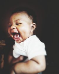 Close-up of cute baby boy over black background