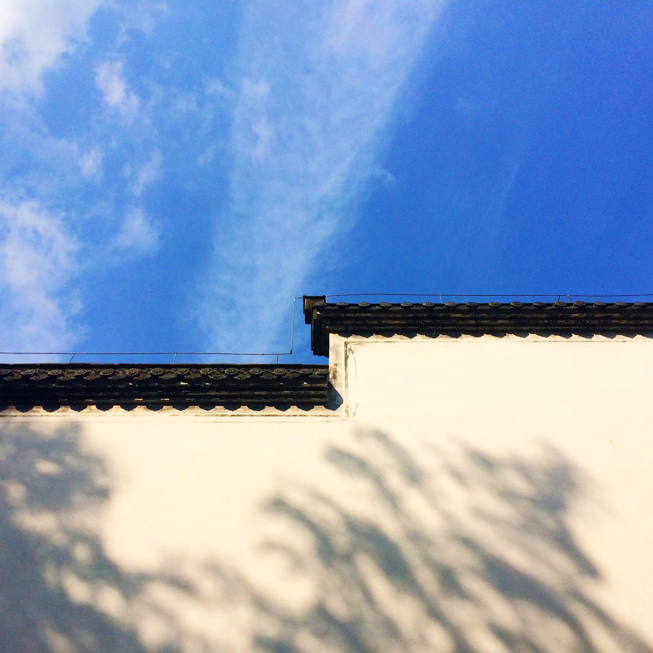architecture, built structure, low angle view, sky, building exterior, blue, cloud - sky, cloud, day, high section, outdoors, sunlight, no people, roof, building, wall - building feature, nature, house, wall, cloudy