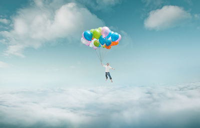 Low angle view of mature man with colorful balloons flying against sky