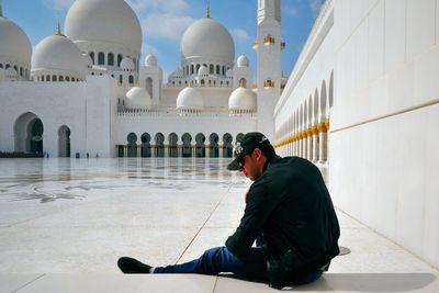 Rear view of man sitting against sheikh zayed mosque