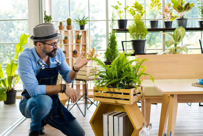 Man kneeling by potted plant at home